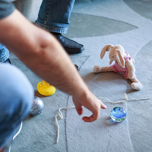 Mensch im Sitzen mit Figuren beinhaltet die systemische Ausbildung. Er zeigt auf eine Glaskugel